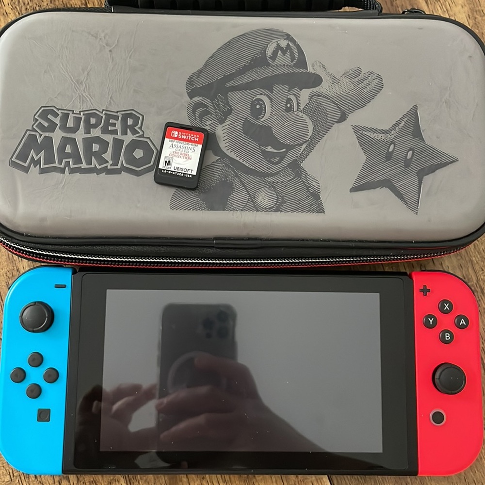Nintendo switch with Mario case and Assasins Creed game.